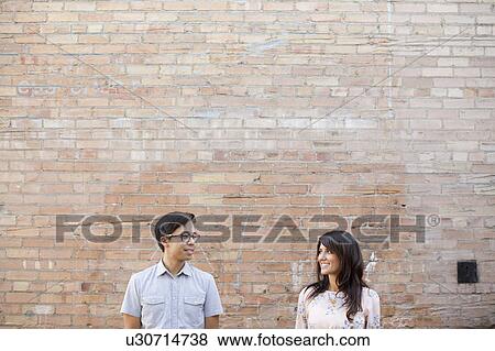 Stock Photo - Couple standing in front of brick wall. Fotosearch