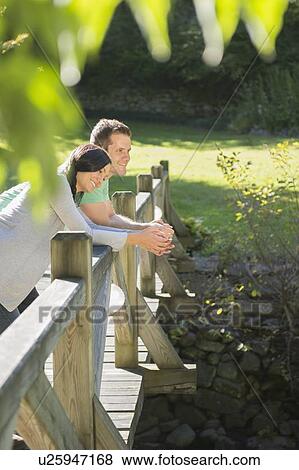 Stock Photo - Couple standing on wooden bridge. Fotosearch