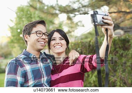 Stock Image - Couple taking self-portrait picture. Fotosearch