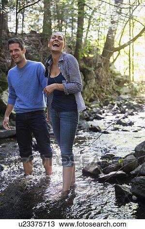 Stock Image - Couple wading in stream. Fotosearch