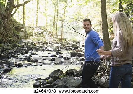 Stock Photo - Couple walking by stream in forest. Fotosearch