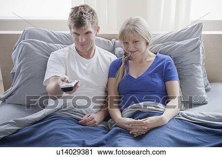 Couple watching television in bed View Large Photo Image Stock Image - Couple watching television in bed. Fotosearch