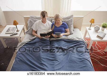 Picture - Elevated view of couple sitting in bed reading. Fotosearch
