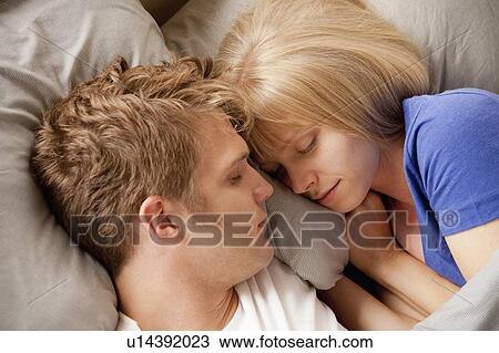 Stock Image - Elevated view of couple sleeping in bed. Fotosearch