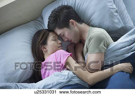 Stock Image - Elevated view of couple sleeping. Fotosearch