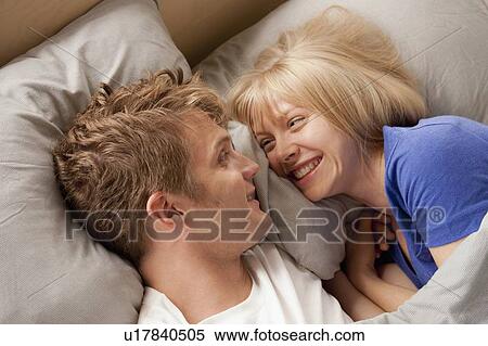 Elevated view of laughing couple lying in bed View Large Photo Image Stock Photography - Elevated view of laughing couple lying in bed. Fotosearch