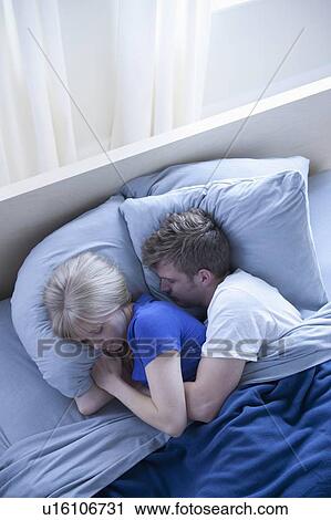 Stock Image - Elevated view of sleeping couple. Fotosearch
