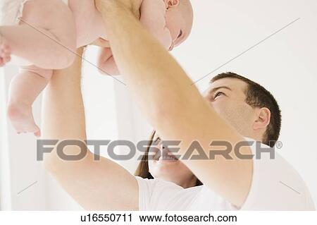 Stock Image - Father holding baby boy (2-5 months). Fotosearch