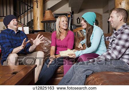 Stock Image - Friends talking in log cabin. Fotosearch