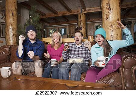 Friends watching tv in log cabin View Large Photo Image Stock Photo - Friends watching tv in log cabin. Fotosearch