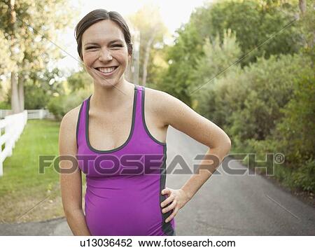 Stock Image - Front view portrait of pregnant mid adult woman in sport clothing. Fotosearch