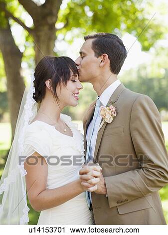 Groom kissing bride in park View Large Photo Image Stock Image - Groom kissing bride in park. Fotosearch