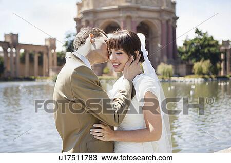 Groom kissing bride in park View Large Photo Image Stock Image - Groom kissing bride in park. Fotosearch