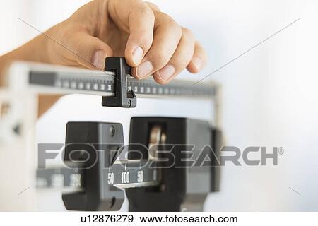 Stock Photo - Hand adjusting weight scales. Fotosearch