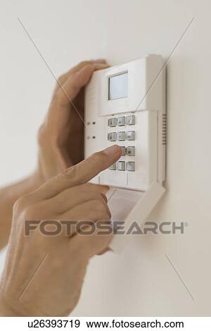 Stock Photo - Hand setting code on burglar alarm. Fotosearch