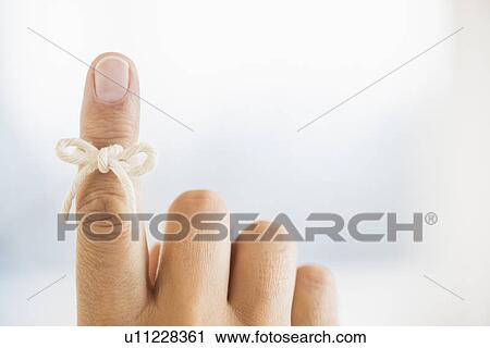 Stock Image - Hand with reminder bow on finger. Fotosearch