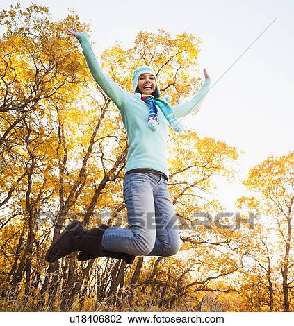 Happy young woman jumping in autumn forest View Large Photo Image Stock Image - Happy young woman jumping in autumn forest. Fotosearch