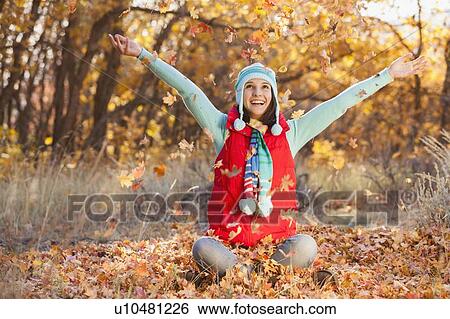 Happy young woman sitting on autumn leaves in forest View Large Photo Image Stock Photograph - Happy young woman sitting on autumn leaves in forest. Fotosearch