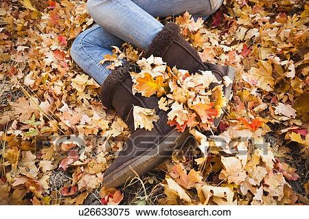 Stock Photography - Legs of young woman lying on autumn leaves. Fotosearch