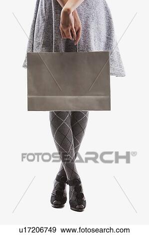 Low section of young woman holding shopping bag, studio shot View Large Photo Image Stock Photo - Low section of young woman holding shopping bag, studio shot. Fotosearch
