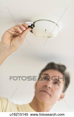 Man changing battery in smoke alarm View Large Photo Image Stock Photography - Man changing battery in smoke alarm. Fotosearch