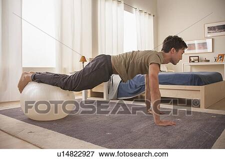 Stock Photo - Man doing yoga using fitness ball. Fotosearch