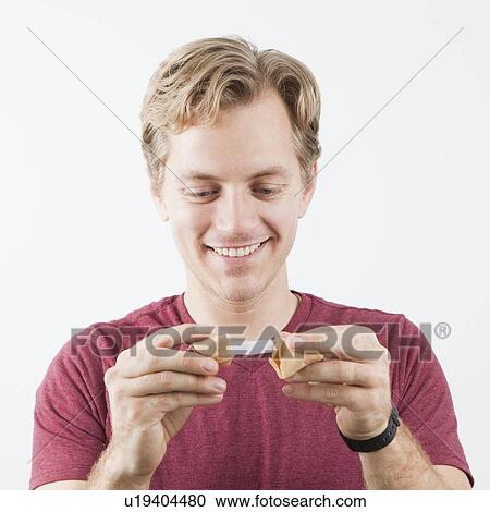 Stock Image - Man holding fortune cookie. Fotosearch