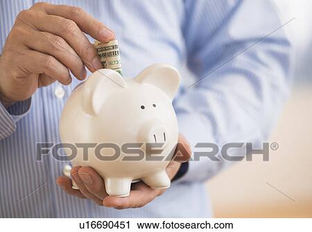 Man inserting money into piggy bank View Large Photo Image Stock Image - Man inserting money into piggy bank. Fotosearch