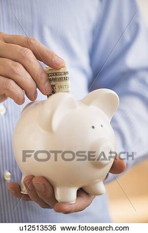 Man inserting money into piggy bank View Large Photo Image Stock Photograph - Man inserting money into piggy bank. Fotosearch