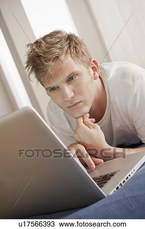 Man lying on bed using laptop View Large Photo Image Stock Image - Man lying on bed using laptop. Fotosearch
