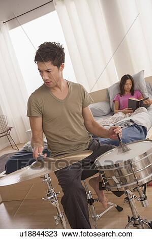 Man plying drums and woman reading in bed View Large Photo Image Stock Image - Man plying drums and woman reading in bed. Fotosearch