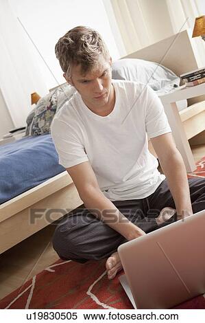 Man sitting on floor using laptop View Large Photo Image Stock Photography - Man sitting on floor using laptop. Fotosearch