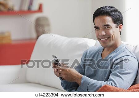 Picture - Man texting in living room. Fotosearch
