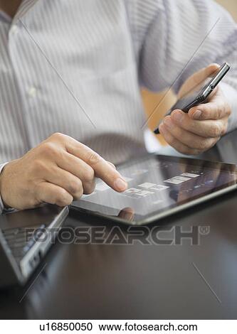 Stock Image - Man using tablet pc, laptop and smartphone. Fotosearch