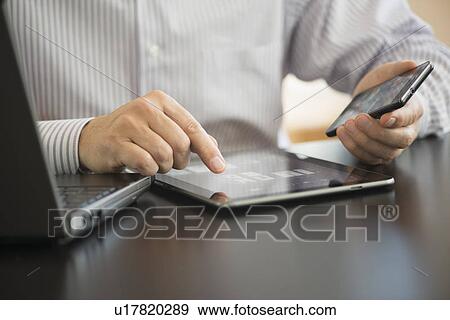 Stock Photo - Man using tablet pc, laptop and smartphone. Fotosearch