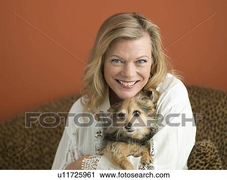 Stock Image - Mature woman playing with dog. Fotosearch