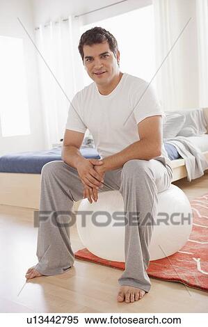 Stock Photography - Mid adult men exercising with fitness ball. Fotosearch