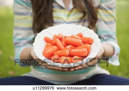 mid-section of mid adult woman holding bowl with carrots in focus View Large Photo Image Stock Photograph - mid-section of mid adult woman holding bowl with carrots in focus. Fotosearch