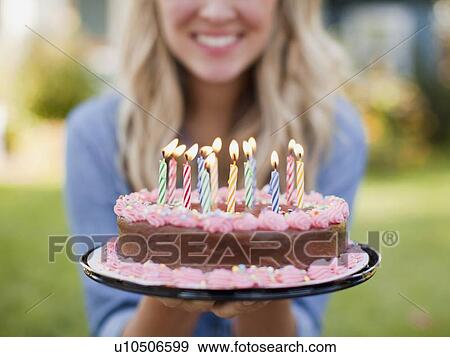 Stock Photo - Mid-section of young woman holding birthday cake. Fotosearch