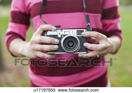 Stock Photography - Midsection of woman holding old camera. Fotosearch