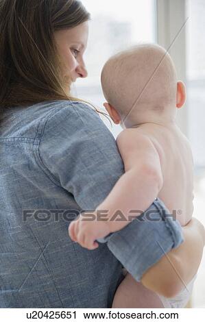Mother holding baby boy (2-5 months) by window View Large Photo Image Stock Image - Mother holding baby boy (2-5 months) by window. Fotosearch