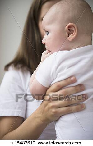 Stock Image - Mother holding baby boy (2-5 months). Fotosearch
