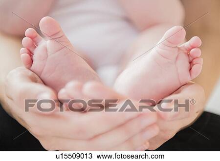 Stock Image - Mother holding feet of baby boy (2-5 months). Fotosearch
