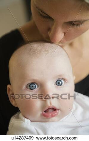 Stock Photo - Mother kissing baby boy (2-5 months). Fotosearch