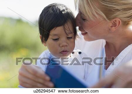Mother reading book to her baby boy outdoors View Large Photo Image Stock Photo - Mother reading book to her baby boy outdoors. Fotosearch