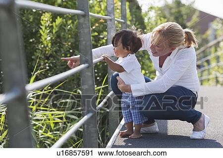 Stock Image - Mother showing something to her baby boy. Fotosearch