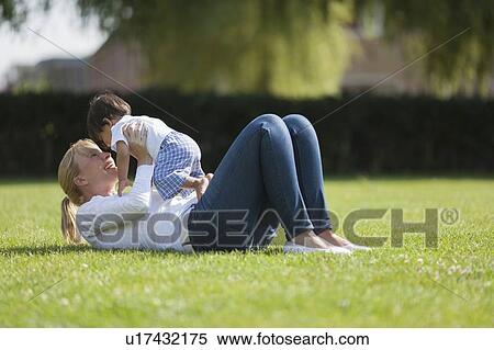 Stock Photography - Mother with baby (6-11 months) playing on grass. Fotosearch