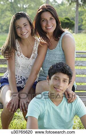 Stock Image - Outdoor portrait of smiling mother with daughter (12-13) and son (14-15). Fotosearch
