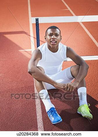 Stock Photo - Portrait of boy (12-13) resting on running track. Fotosearch