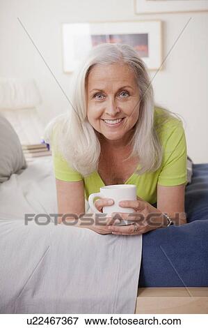 Stock Photo - Portrait of cheerful senior woman holding coffee cup. Fotosearch